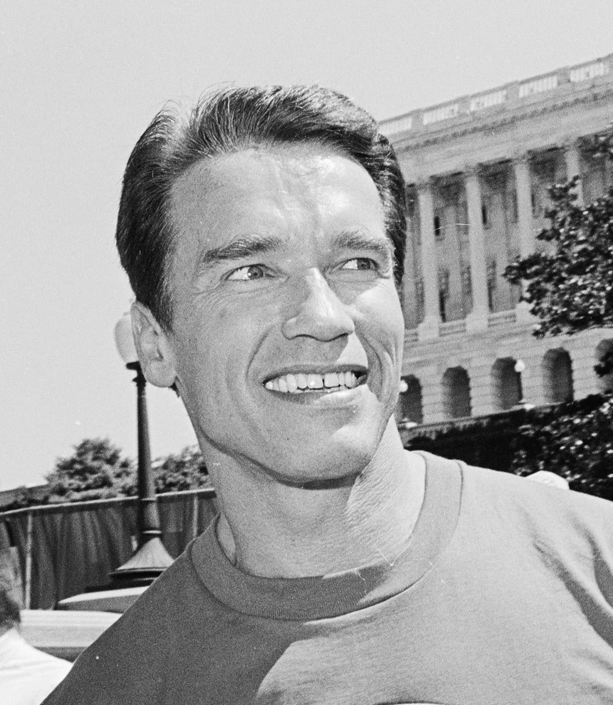 Black-and-white portrait of Arnold Schwarzenegger smiling near the U.S. Capitol in 1991